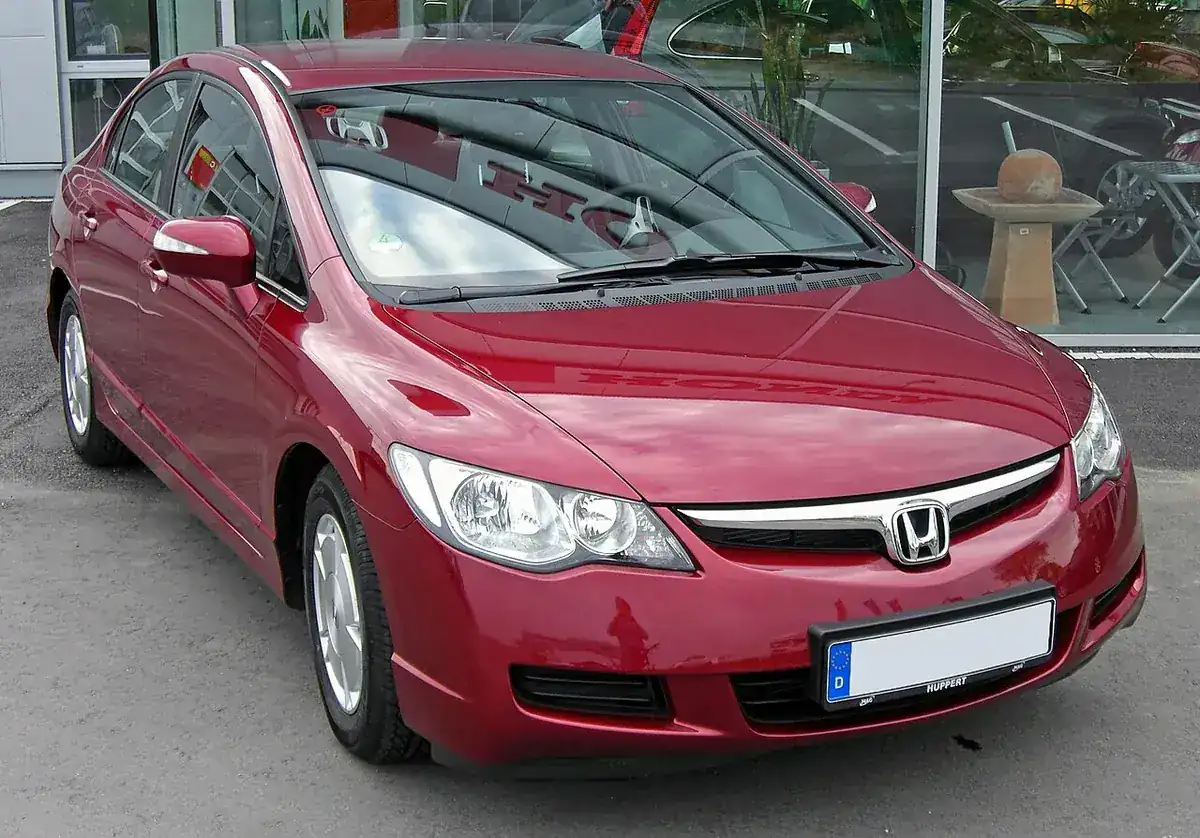 Red eighth-generation Honda Civic Hybrid sedan viewed from the front and side
