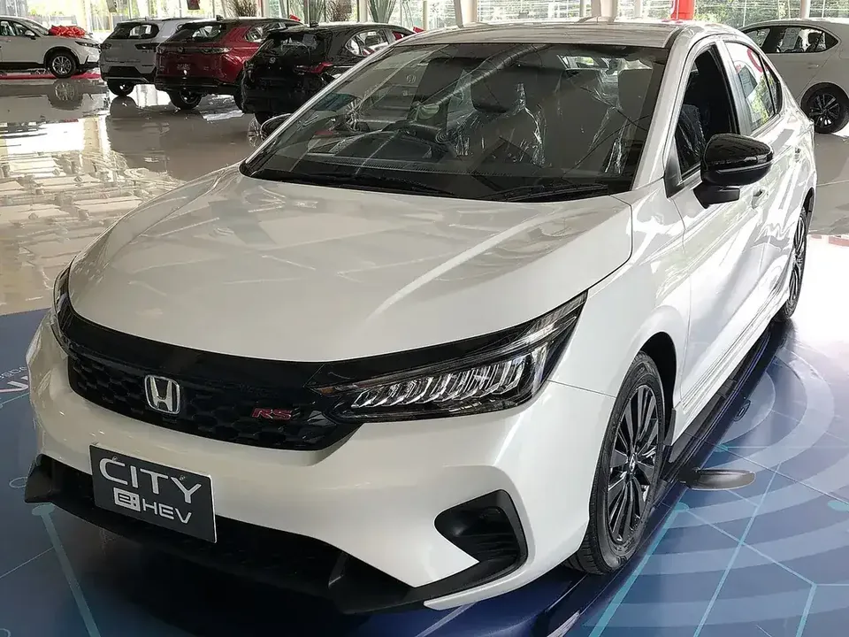 White 2023 Honda City e:HEV RS sedan viewed from the front and side in a Thailand showroom