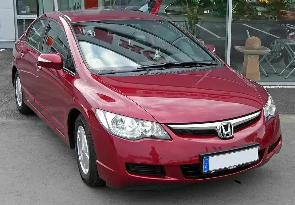 Red eighth-generation Honda Civic Hybrid sedan viewed from the front and side