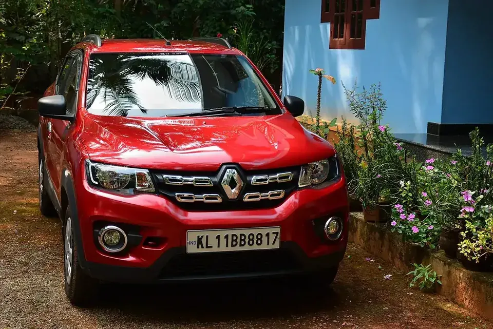 Red Indian Renault Kwid RXT(O) seen from the front among trees