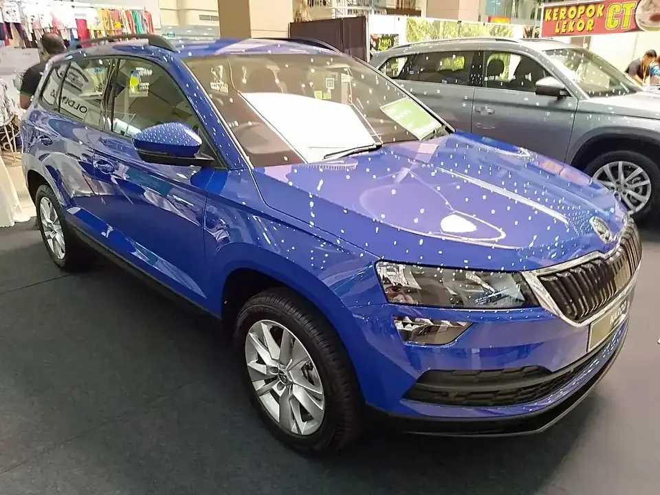 Blue pre-facelift Škoda Karoq seen from the front and side at a mall display