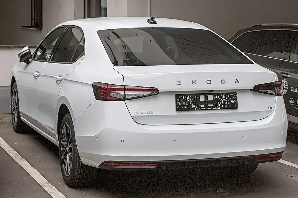 White fourth-generation Škoda Superb liftback viewed from the rear and side