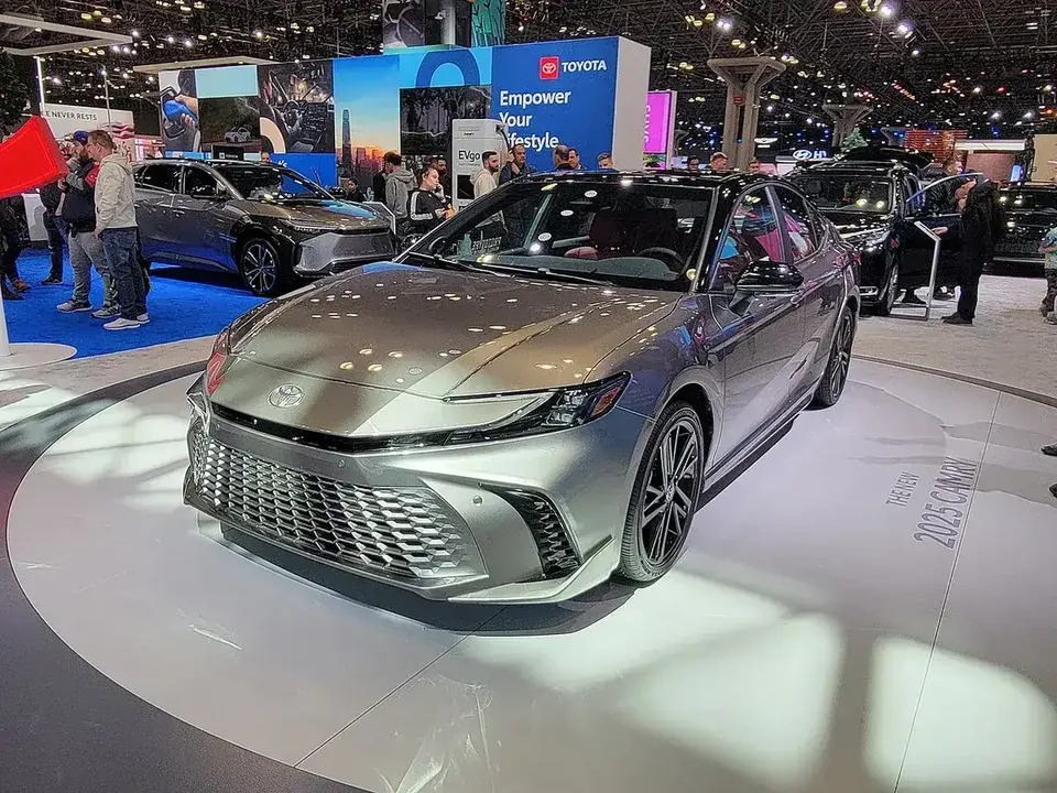 Silver Toyota Camry Hybrid XLE XV80 viewed from the front and side at a motor show