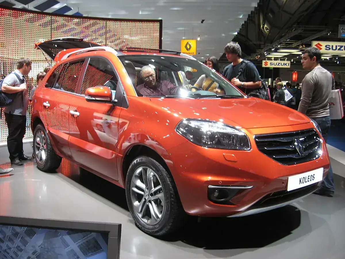 Orange first-generation Renault Koleos Phase II viewed from the front and side at a motor show
