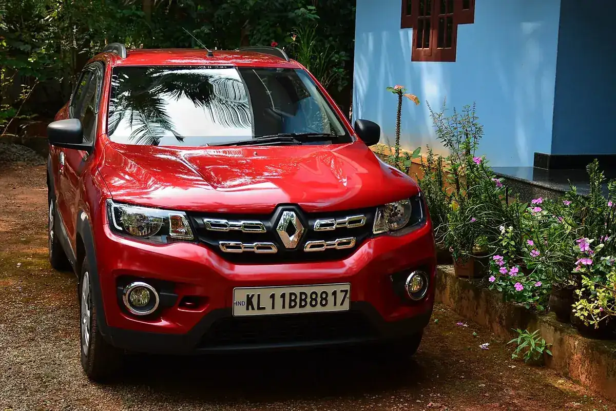Red Indian Renault Kwid RXT(O) seen from the front among trees