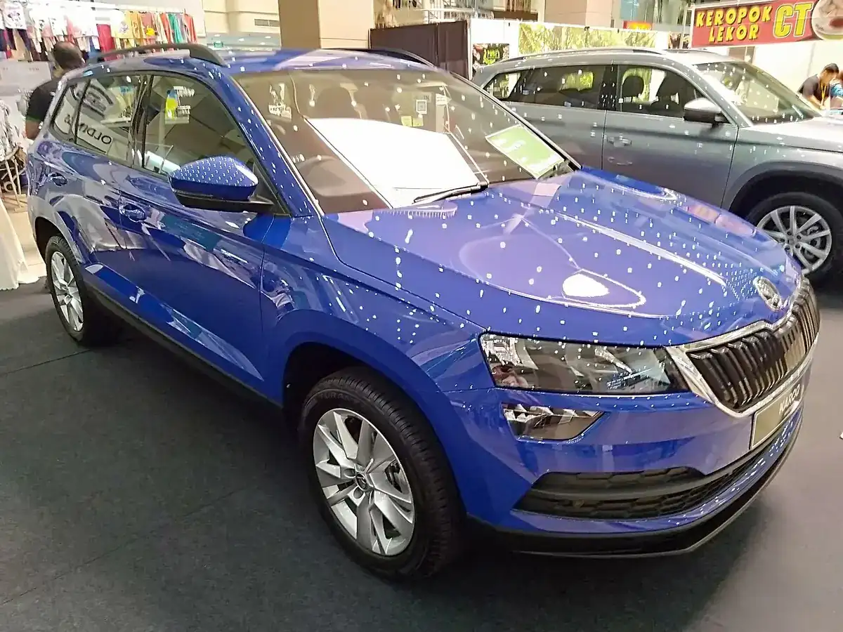 Blue pre-facelift Škoda Karoq seen from the front and side at a mall display