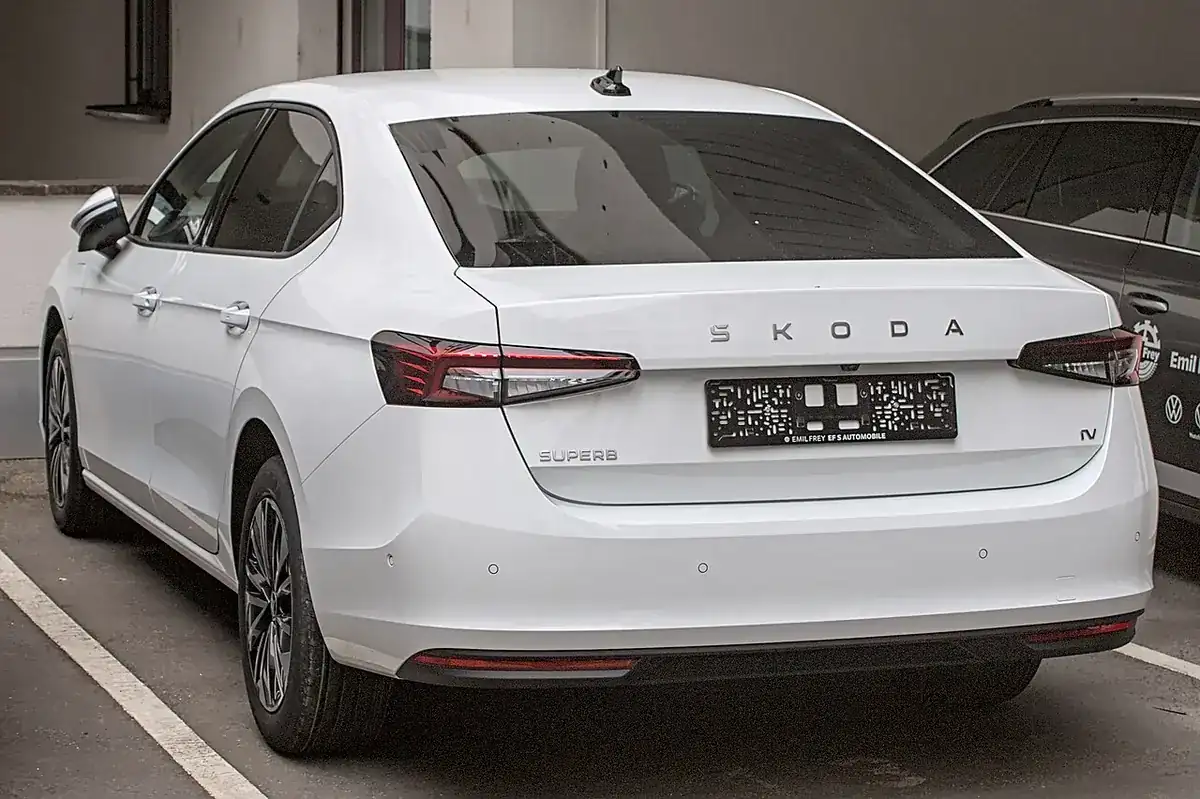 White fourth-generation Škoda Superb liftback viewed from the rear and side