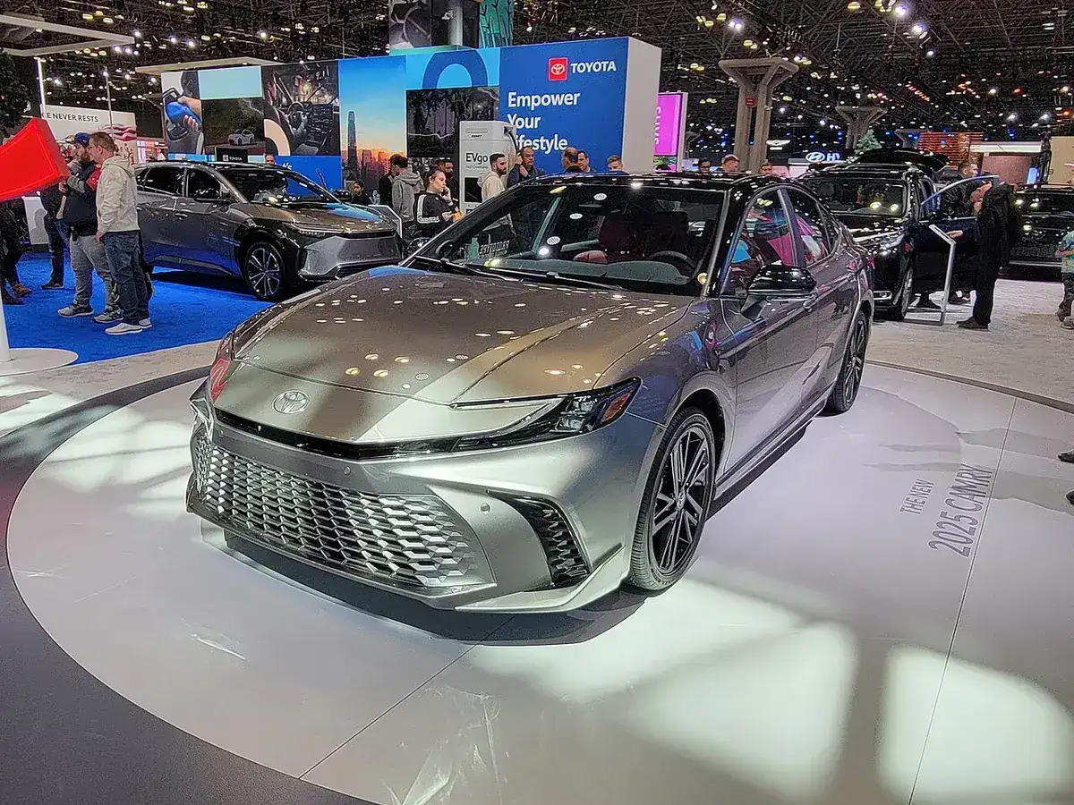 Silver Toyota Camry Hybrid XLE XV80 viewed from the front and side at a motor show